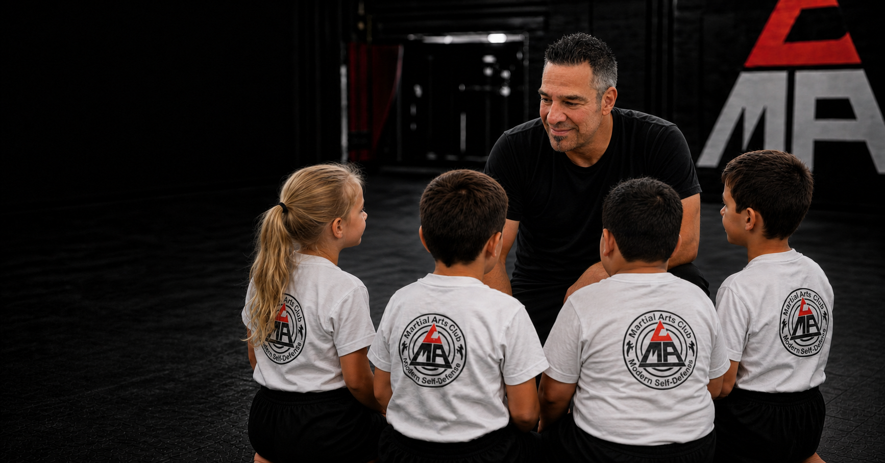 Trainer Jürgen spricht auf Augenhöhe mit vier Kindern in weißer Clubkleidung